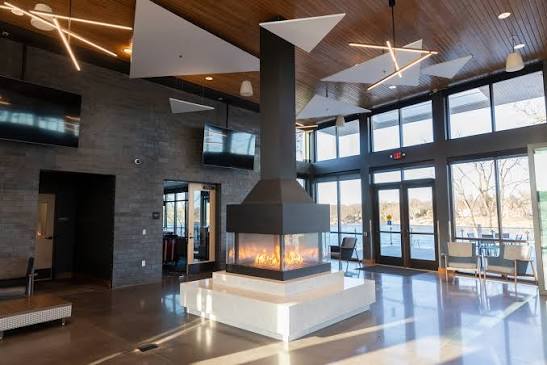 Modern lobby with a central fireplace and river views inside the Mississippi Crossings Event Center
