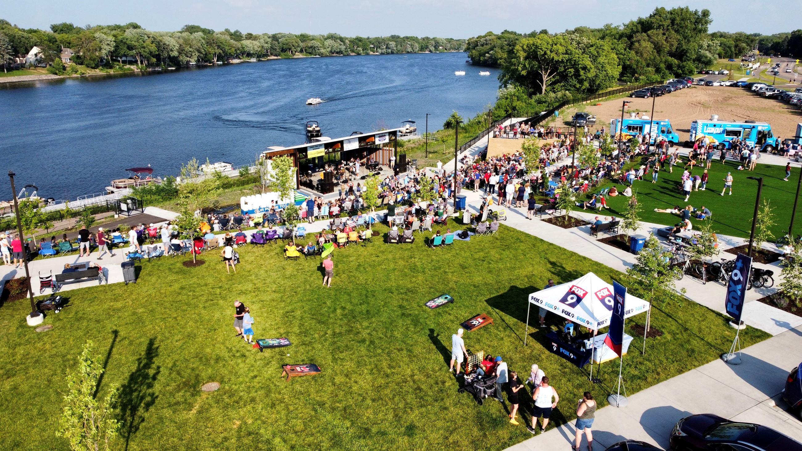 Crowd gathered for an outdoor summer concert and food trucks at Mississippi Crossings in Champlin