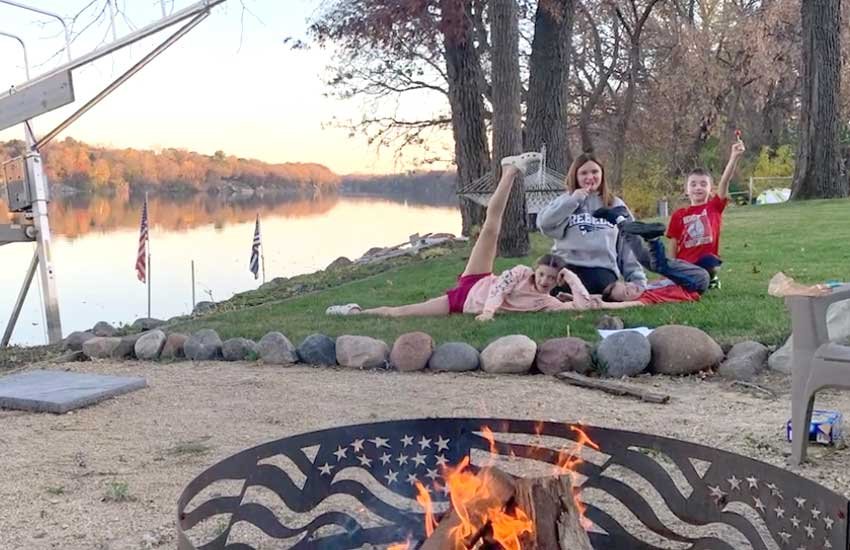 The Sabas kids enjoying a bonfire night along the Mississippi River with American flags and fall foliage